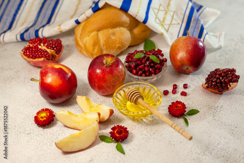 Rosh Hashanah, the Jewish New Year. Traditional symbols are tallit, apples, pomegranate, hala bread and honey on a light background. Happy Rosh Hashanah. Shana Tova.