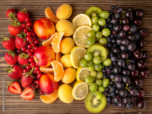 Fresh summer berries and fruits on a wooden background. Healthy eating concept. Assortment of healthy vegetarian food. Top view.