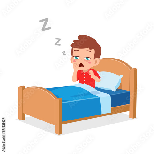 A sleepy little boy yawning widely while sitting in his wooden bed with a blue blanket and white pillow