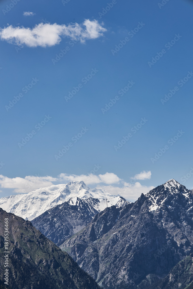 Obraz premium Majestic snow-capped mountain peaks under a clear blue sky, illustrating natural grandeur and serene wilderness. Scenic landscape for travel and adventure.