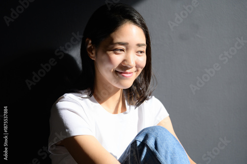 グレー背景で自然光を浴びる日本人女性