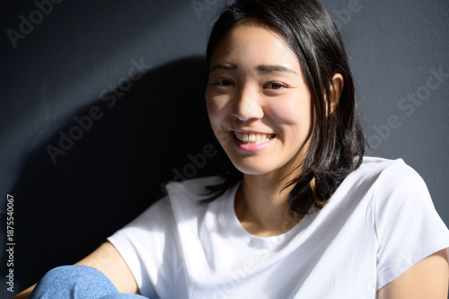 グレー背景で自然光を浴びる日本人女性