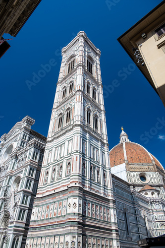 Detailed view of Santa Maria del Fiore cathedral in Florence, showing the iconic red dome and the nearby bell tower, highlighting the rich Renaissance architecture and historic elegance.