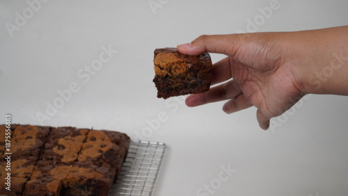Hands holding brownies cookies (brokies) with a white background.
