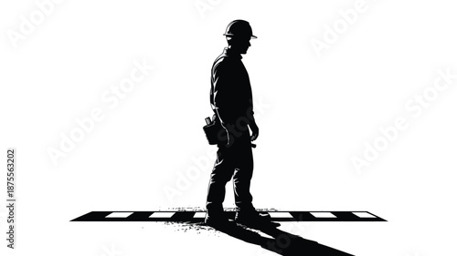 Silhouette of a construction worker in hard hat standing on road