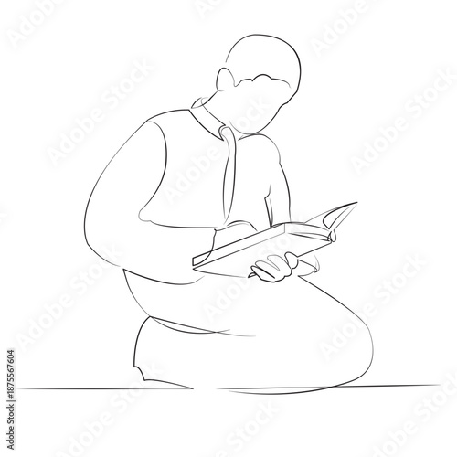 A teenage boy prays and reads the Koran.