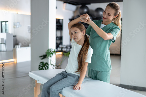 Bilde på lerret Woman therapist performing little girl neck treatment sitting behind
