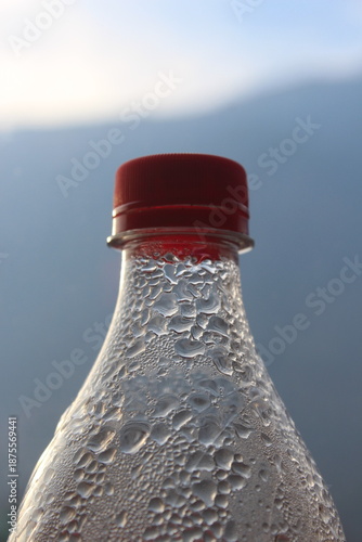 Minimal Glass Bottle with Red Cap Against Blue Sky
