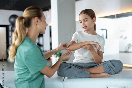 Young girl receiving first aid as healthcare worker applies bandage
