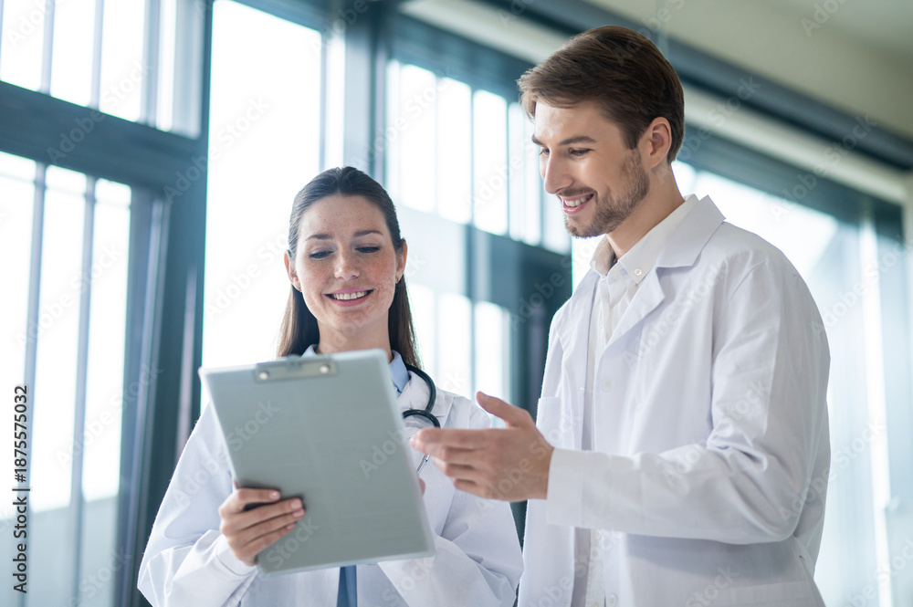 Obraz premium Two doctors talking in the clinics corridor and looking contended