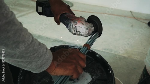 Workers hands holding a metal cutter, grinding the edges of a group of iron bars, creating some sparks in slow motion.