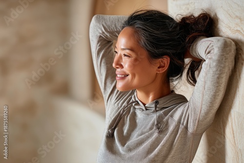 happy asian woman in her 40s showing off a thermal merino wool top while standing against soothing spa interior