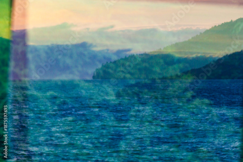 A reflection in window glass of the forest, mountains and moving water.