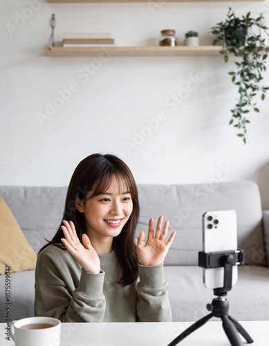 Young asian woman recording video blog or vlog on smartphone at home