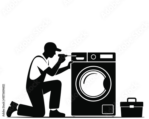 Technician repairing a washing machine with a toolbox nearby