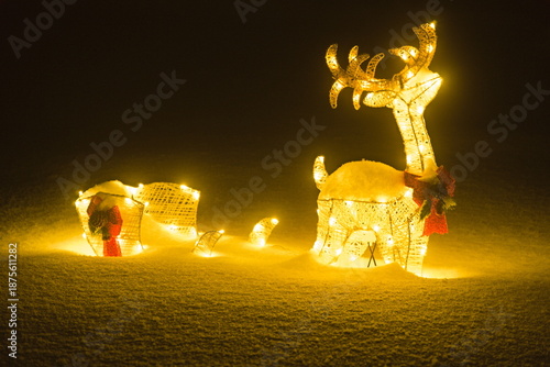 beleuchtetes Rentier mit Schlitten im Schnee
