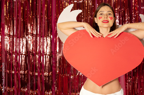 A cute cupid girl with wings and a big red heart on her body, symbolizing love, romance, and affection. Copy space for text.