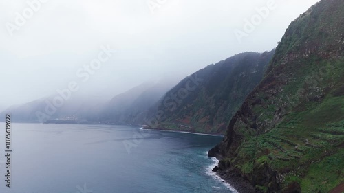 Velvety clouds drift past towering escarpments above gentle sea shores