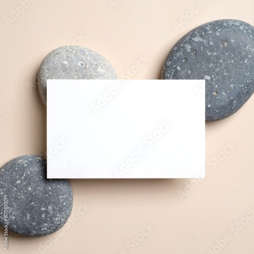 A pristine white card rests atop a rugged pile of textured gray rocks, surrounded by natural earthy tones, creating a serene and minimalist scene.