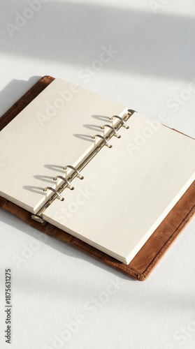 Agenda vintage de piel con anillas hecha a mano con papel blanco reciclado para tomar notas del día a día como agenda, diario, cuaderno de viajes, con iluminación natural sobre un fondo blanco.