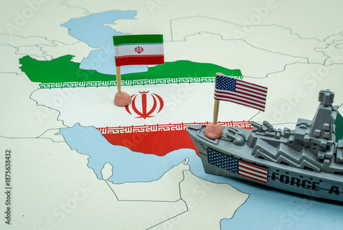 United States and Iran national flags on a geopolitical map with a toy warship, representing a potential military conflict or diplomatic tension between the two countries