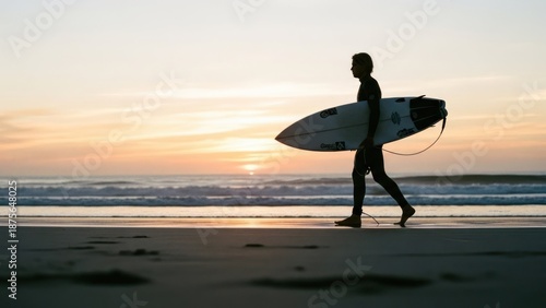 Silhouette of surfer walking on the beach at sunset, holding a surfboard, with ocean views