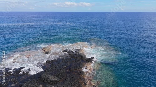 Wide aerial drone footage starting with a coastal view before tilting down to reveal the submerged volcanic shoreline, then rising again toward a wide horizon view in Reunion Island