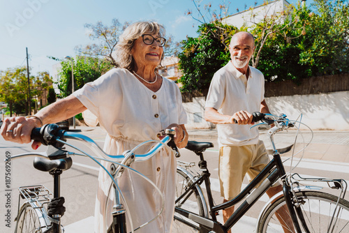 Happy senior couple walking bicycles enjoying active retirement