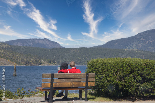 Couple sitting on a bench overlooking a beautiful lake and mountains