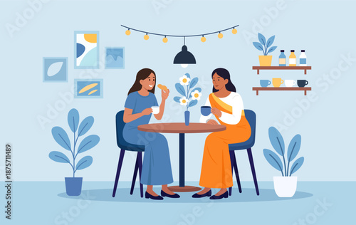 European woman and her Indian friend are drinking tea together. Smiling women gossiping spending time at cafeteria. Cheerful diverse friends are gathered at cafe, enjoying coffee break, conversation