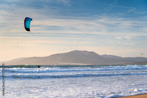 Kitesurfer with kite against sky at sunset on coast famous surf spot in Spain, Tarifa, Atlantic Ocean.
