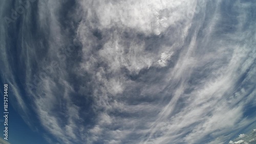 Time lapse with fisheye lens of white summer clouds moving through a blue sky
