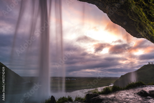 View of powerful Seljalandsfoss waterfall cascading down, contrasted against the expansive sky and rugged landscape, South Island, Iceland.