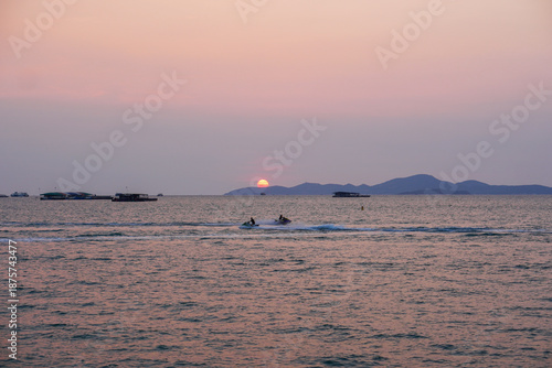 Serene Sunset Over Ocean with Jet Skiers and Islands in Background