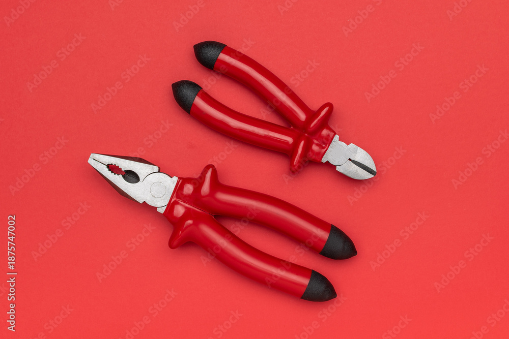 Obraz premium Top View of Pliers and Wire Cutters on Vibrant Red Background