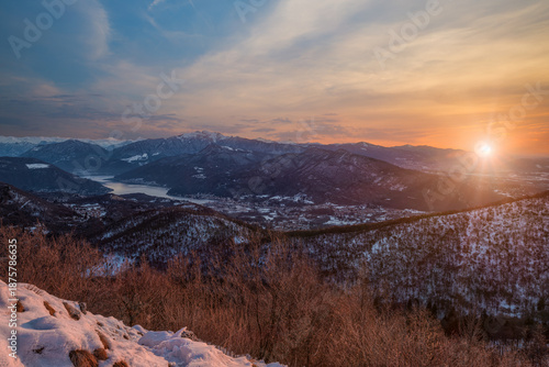Lake Lugano, Italy, from mount Poncione. Beautiful winter sunrise from above, with snow capped mountains, woods, and a lake. Below you can see the town of Porto Ceresio, Besano and Monte San Giorgio