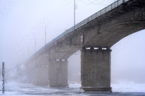 Frozen bridge over icy river with snow and icicles in winter landscape