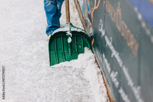 Photography Photo of a man cleaning snow from ice with a shovel, cleaning at an ice rink