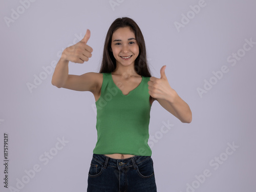 Happy young woman showing thumbs up gesture and smiling on white background