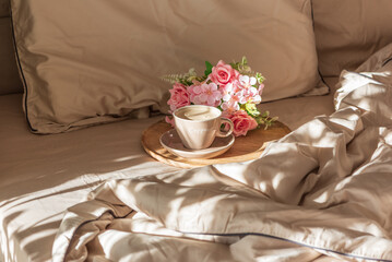 Cappuccino Cup and Flowers on Tray with Satin Bedding in Sunlight. Valentine's or Mother's Day Celebration