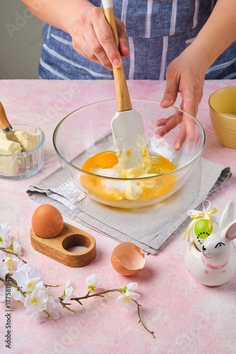 Step by step preparation of Easter cake or other Easter pastries on pink concrete background. Rubbing butter with eggs and sugar. Happy Easter.
