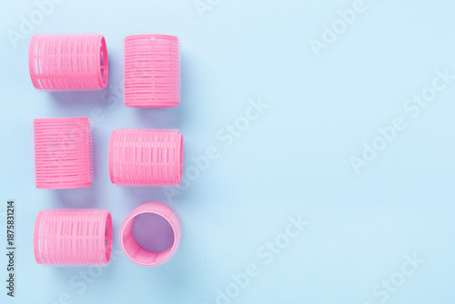 Photos Pink hair curlers on color background, top view