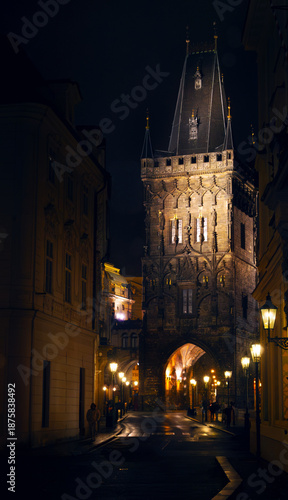 Foto Dramatic night view of the Powder Tower (Prašná brána) in Prague, Czech Republic, illuminated by warm glowing street lights, moody and atmospheric evening