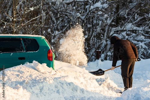 Wallpaper Mural Hooded man digs out a car buried in heavy snow, showering fresh powder in bright winter sunlight. A common post-blizzard scene. Balkan cyclone Francis in Central Russia, January 2026 Torontodigital.ca