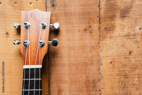 Photography A classic brown acoustic ukulele with white wooden strings rests on a rustic woo
