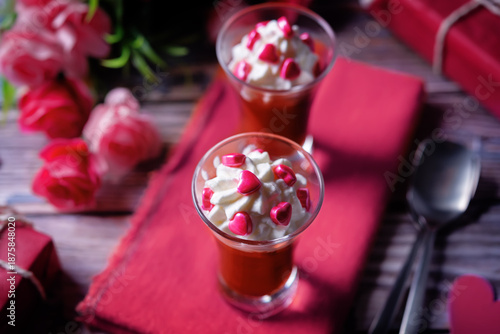 Cherry jello shots in a glass with whipped cream and pink heart cookie topping for Valentine's day holiday