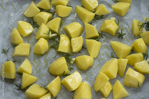 raw potato wedges with rosemary on baking tray