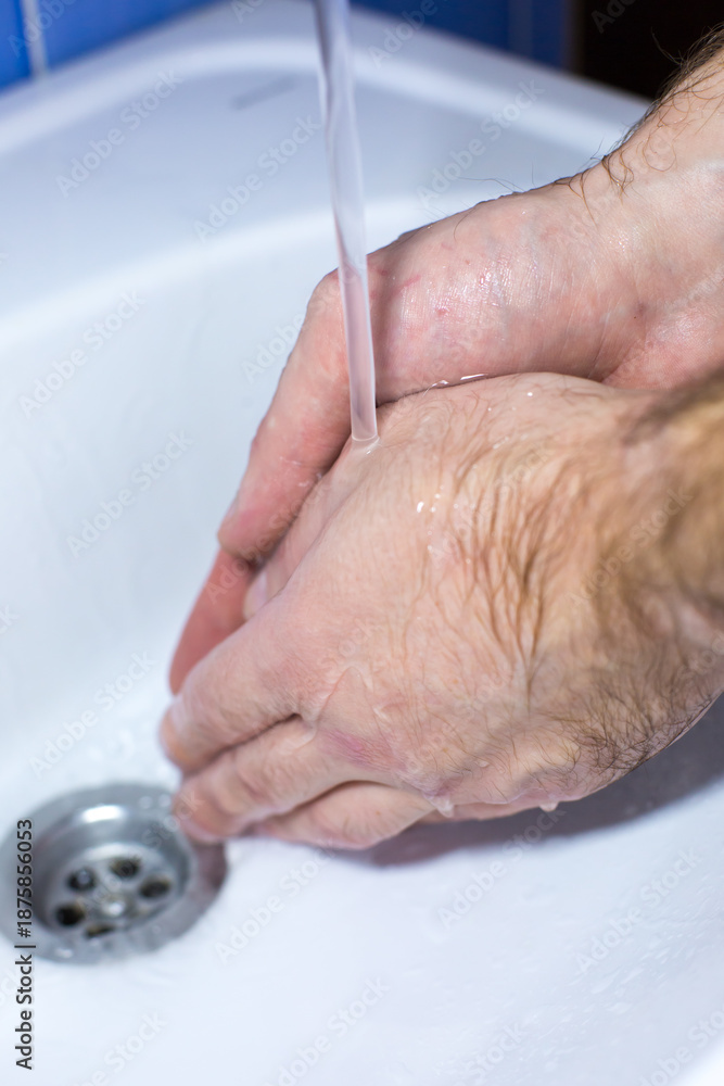 Fototapeta premium Close-up of hands washing under running water in a sink, showcasing hygiene practices and cleanliness, emphasizing the importance of handwashing in daily routines
