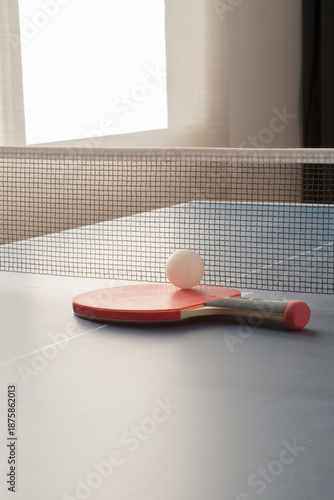 Red racket and white ball on table tennis indoors