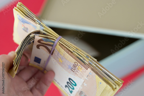 Human hand checking a bundle of euro banknotes with rubber band